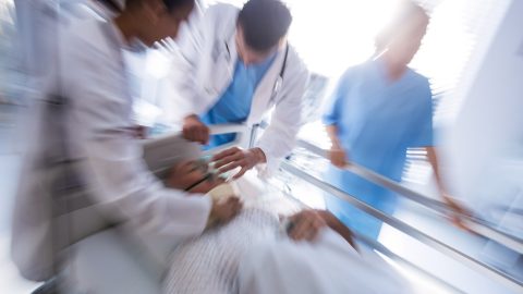Team of doctors putting oxygen mask on a male senior patient face in the hospital